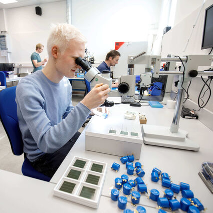 Employee in lab looks into a microscope